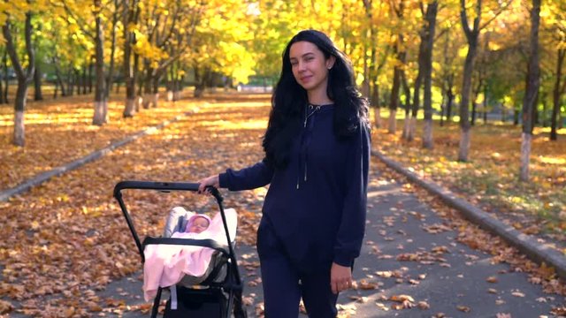Young woman pulling baby stroller in park