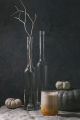 Glass of pumpkin layered spice latte with pumpkin puree, milk foam and cinnamon standing with...