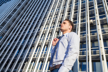 Businessman in classy suit holding his jacket on background of modern office skyscraper.