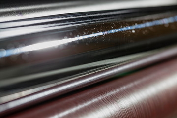 Rolling shafts in the paint of industrial printing machine. Offset printing.