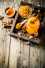 Spicy buckthorn (hippophae) drink - tea, juice or smoothie, with cinnamon and anise, rustic wooden background copy space