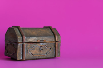 An old metal box on pink background.