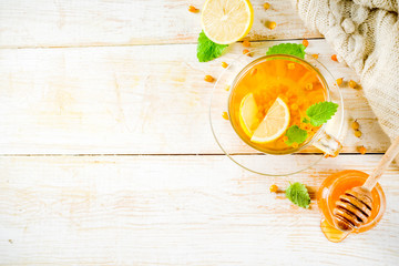 Homemade buckthorn, Hippophae, mint and honey tea wooden background copy space top view