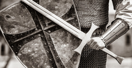 Closeup view on traditional medieval knight with shield and sword. Image in black and white color style - obrazy, fototapety, plakaty