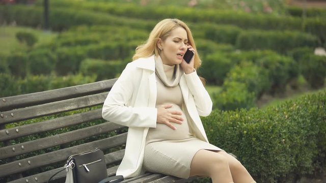 Pregnant woman calling hospital phone, suffering abdominal pain, prenatal care