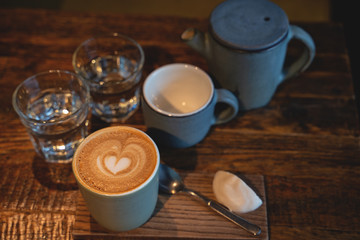 Two cups of coffee and a glass of water on rustic wooden table. Close-up