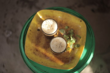 aerial close up of traditional african tea - black strong green attaya in small glasses on a yellow plate, outdoors in the Gambia, Africa