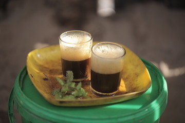 close up of traditional african tea - black strong green attaya in small glasses on a yellow plate, outdoors in the Gambia, Africa
