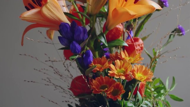 Slow Motion Tracking Shot Over A Colorful Flower Bouquet With Gerbera Daisies, Purple Statices, Orange Lilies, Blue Gentiana, Greens And Millet Grass.