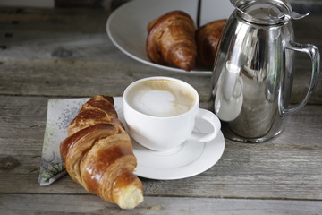 croissant and a cup of coffee on wooden background