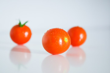 Three cherry tomatoes on the white surface