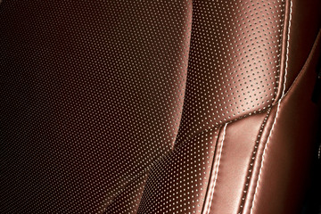 Modern luxury Car brown leather interior. Part of leather car seat details with white stitching....
