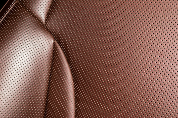 Modern luxury Car brown leather interior. Part of leather car seat details with white stitching. Interior of prestige car. Comfortable perforated leather seats. Brown perforated leather.