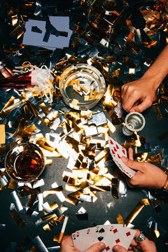 cropped image of male friends playing poker at table covered by golden confetti