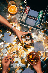 cropped image of women celebrating with alcohol, cigarettes and poker chips with playing cards on...