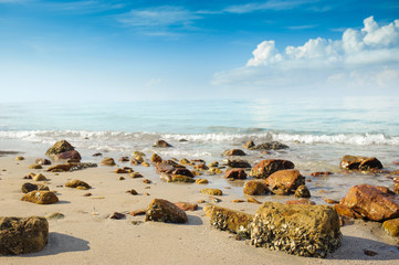 Fototapeta na wymiar sandy beach with rocks against ocean blue sea and nice blue sky