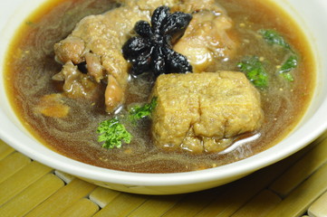 boiled chicken leg and fried tofu with Chinese herb in brown soup on bowl
