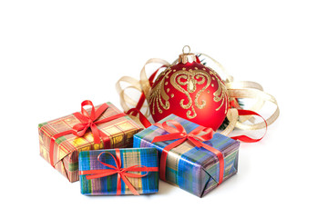 Christmas gifts, boxes in colorful wrapping paper tied with red ribbons and red ball with golden decoration. 