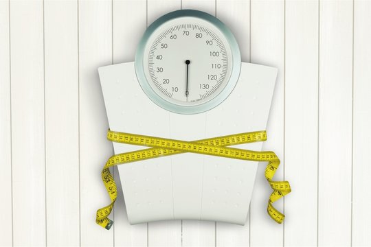 Bathroom scale with a measuring tape on background