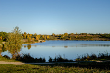 Lake on an autumn day. Autumn colorful foliage with lake reflection.