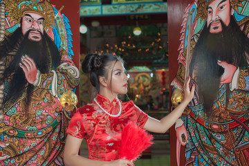 Asian young female model fashion red Chinese dress in the China shrine. Asian girl in red Chinese dress happy Chinese new year in the China temple Thailand 