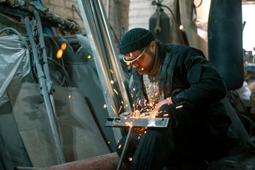 The worker cuts the steel with an electric grinding wheel