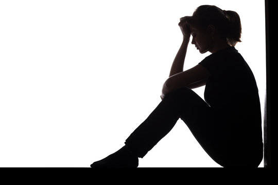silhouette of a woman sitting on the floor in a corner on a white isolated background, a sad girl thinking about problems, concept of depression