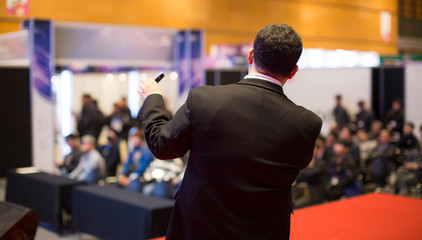 Presenter Presenting on Stage at Conference Meeting. Speaker at Professional Lecture. Unidentifiable Blurred De-focused. Tech Presenter and Audience. Corporate Executive Manager Presentation Seminar.
