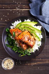 Fototapeten Salmon teriyaki rice bowl with spinach and avocado. View from above, top studio shot © freeskyline