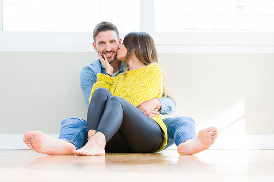 Beautiful young couple in love, kissing and hugging each other sitting on the floor at home