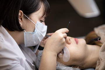 Naklejka premium Eyelash extension procedure . Master and a client in a beauty salon