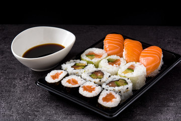 sushi assortment on black tray and soy sauce