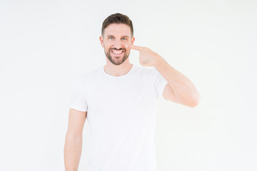 Obraz premium Young handsome man wearing casual white t-shirt over isolated background Pointing with hand finger to face and nose, smiling cheerful