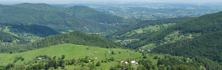 Fototapeta na wymiar Mountains, green forests, pastures and a village in the Carpathians in summer, aerial view, panorama