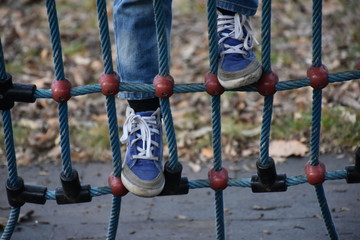 The child is climbing the net on the playground
