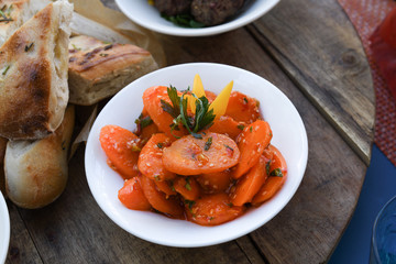 Spicy carrot salad in white bowl on wooden background