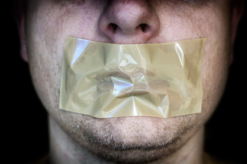 Klebeband vor dem Mund eines Mannes als Symbol nicht existierender Meinungsfreiheit