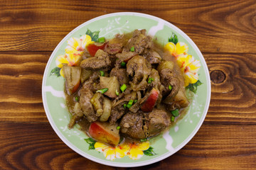Stewed chicken liver with apple and onion on wooden table