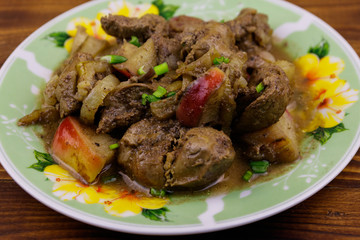 Stewed chicken liver with apple and onion on wooden table