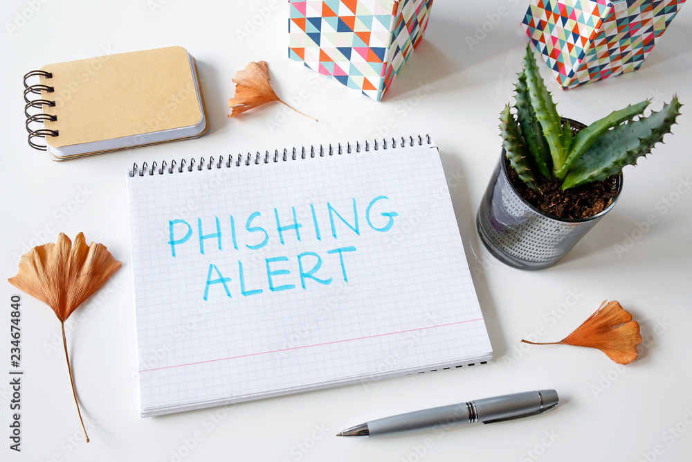 Poster phishing alert written in a notebook on white table
