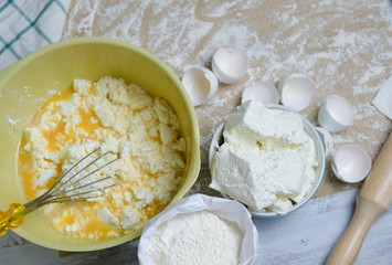 Cooking process of homebaked cottage cheese pie. Raw ingredients in bowl, Table with kitchen objects. Top view flat lay