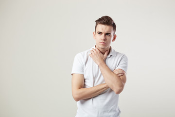 Thoughtful  guy dressed in a white t-shirt and jeans is on a white background in the studio