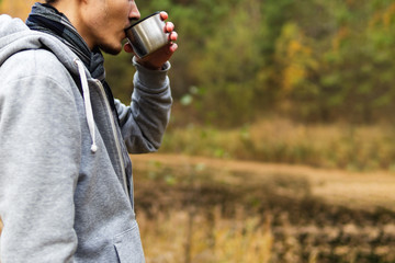 Man drinking hot tea from a thermos in nature