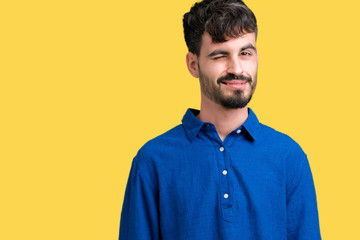 Young handsome man over isolated background winking looking at the camera with sexy expression, cheerful and happy face.