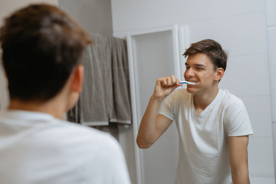 teenage boy brushing teeth in bathroom