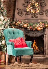Christmas room, firewood burning in the fireplace, a green armchair with red pillows and a Christmas tree with gifts