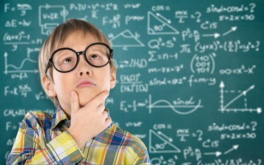 Cute little schoolgirl in glasses on blackboard background