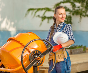 Beautiful girl is engaged in construction using a concrete mixer