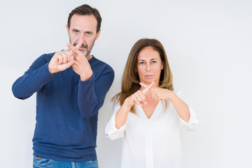 Beautiful middle age couple in love over isolated background Rejection expression crossing fingers doing negative sign