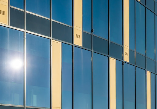 Reflection of the sun on a modern building with a facade of glass and concrete.